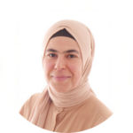 Porträt einer Person mit hellem Kopftuch und beigem Oberteil, die ruhig in die Kamera blickt. Der Hintergrund ist hell und schlicht.